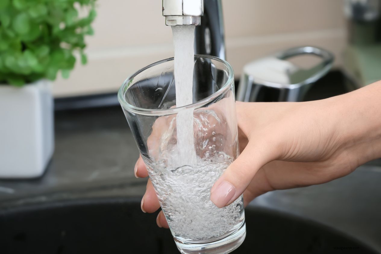 Glass of water being filled at a sink
